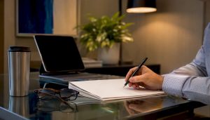 Hand placing pen on project charter document
