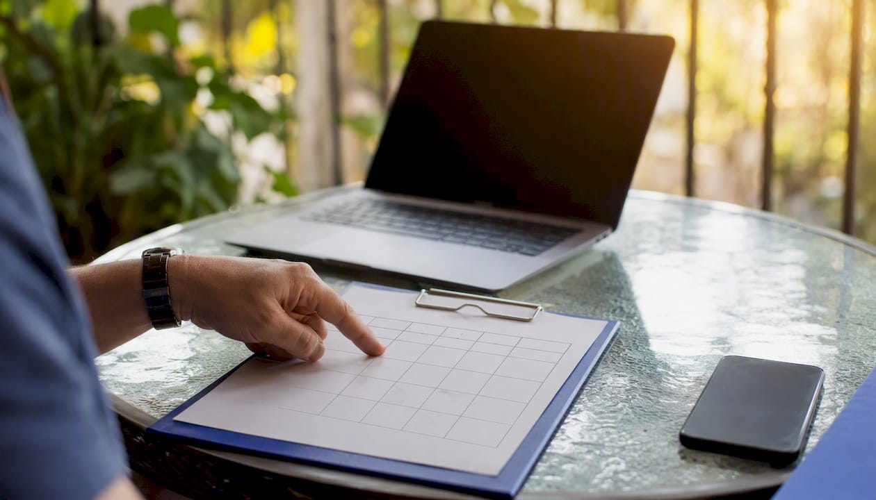 Hand pointing at decision matrix on clipboard