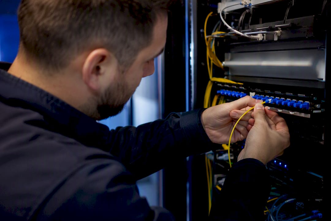 Hands fixing fiber optic cables in telecom panel