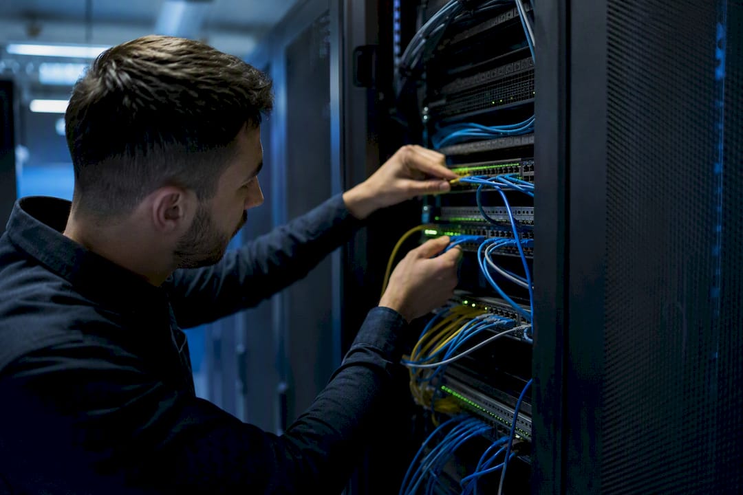 Hands managing fiber optic cables in data center