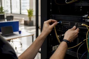 Hands connecting fiber optic in server rack