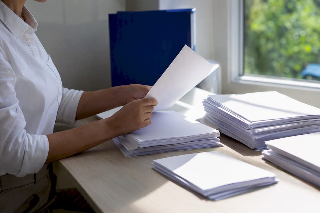 Hands organizing blank invoice papers on desk